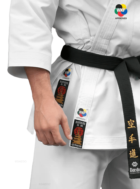 Detalj av WKF-godkänd godkännandeetikett och Daedo-logotyp broderad på karate gi.