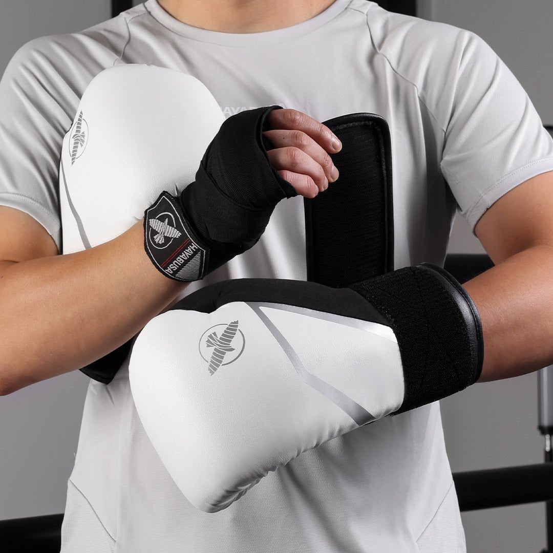 Atleta usando luvas de boxe brancas Hayabusa E1 em posição de guarda