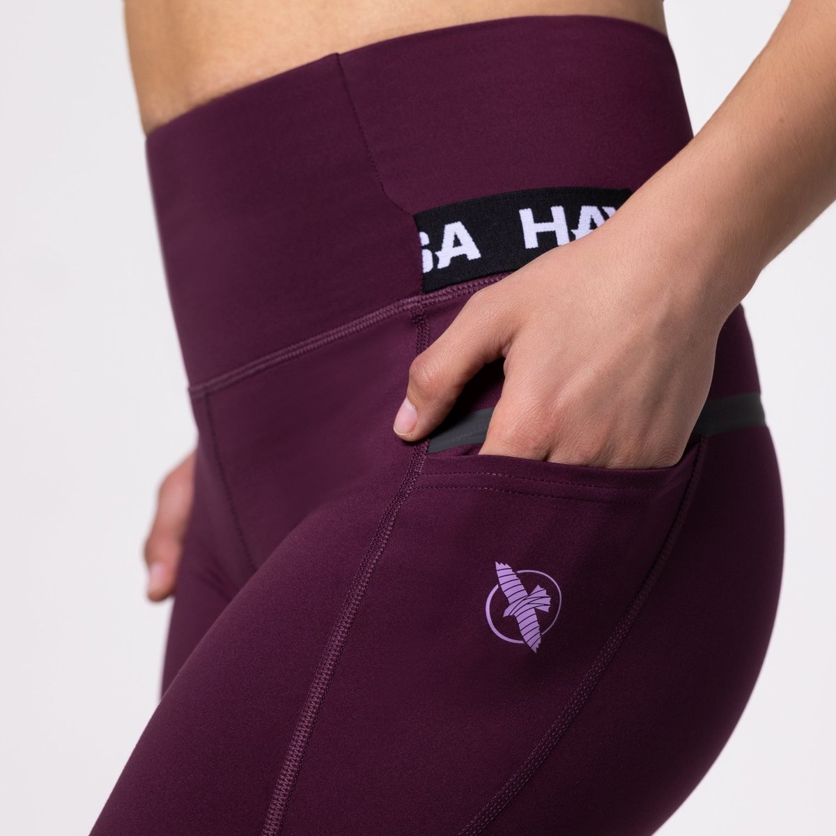 Detalj av den dolda sidfickan på de vinfärgade sportleggingsen