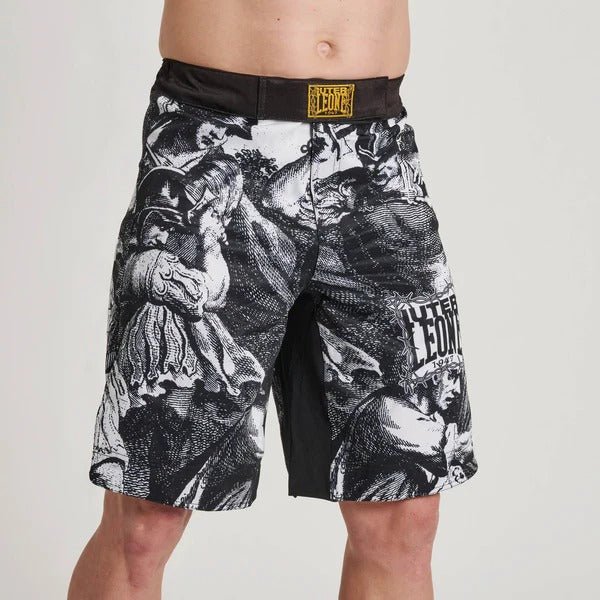 Närbild framifrån av LEONE x IUTER taggtråds MMA-shorts på en modell, som visar det detaljerade grafiska trycket i klassisk gravyrstil och logotyper på ben och midjeband