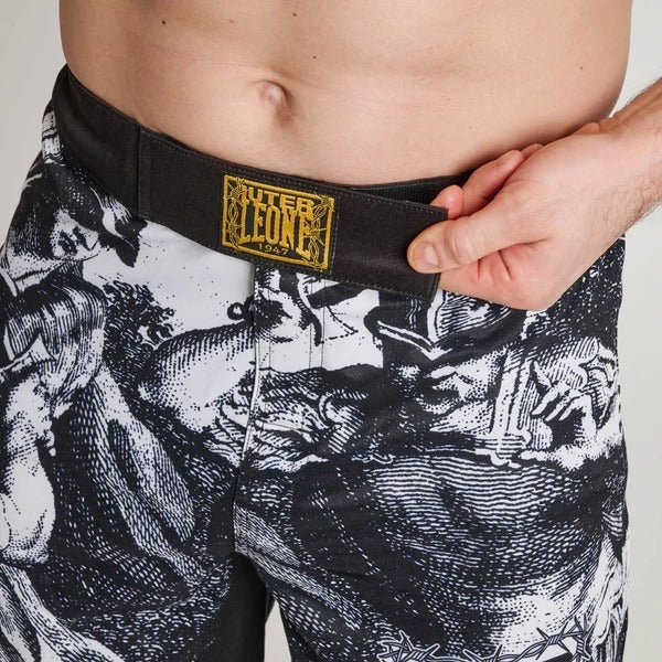 Närbild av den främre stängningspanelen på LEONE x IUTER-shortsen, som visar det invändiga dragskoet och guldtrådslappen på midjebandet