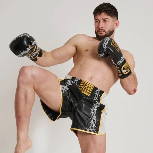 Atleet in Muay Thai kick pose toont de flexibiliteit van prikkeldraadshorts