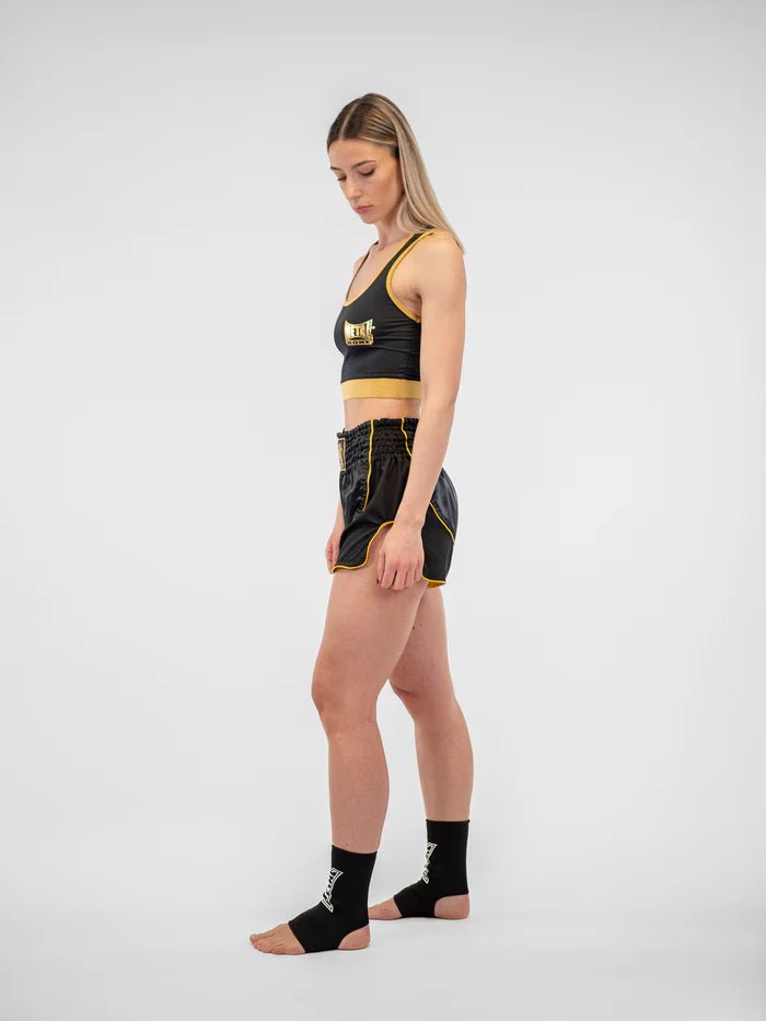Side view women's Metal Boxing Siam black gold shorts, detail of the kick vent