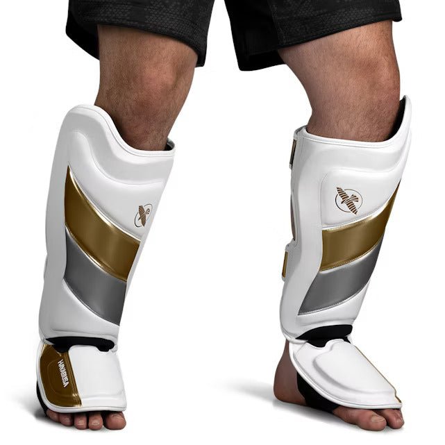 Front view of the white and gold Hayabusa T3 Striking shin guard, showing the pre-curved padding