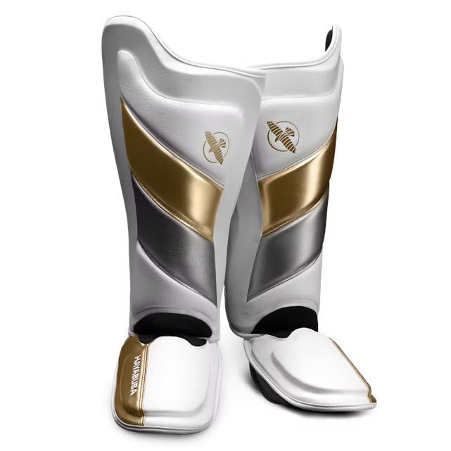 Pair of white and gold Hayabusa T3 Striking shin guards for kickboxing and MMA, front view
