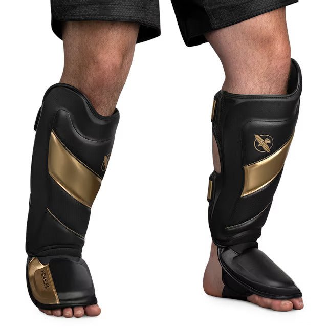 Front view of the black and gold Hayabusa T3 Striking shin guard, showing the pre-curved padding