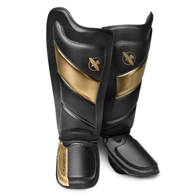 Paire de protège-tibias Hayabusa T3 Striking noirs et dorés pour kickboxing et MMA, vue de face