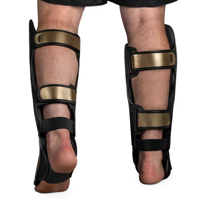 Rear view of the black and gold Hayabusa T3 Striking shin guard, detailing the adjustable closure straps