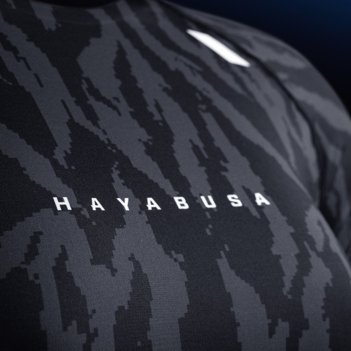 Detalj av skriften och Hayabusa-logotypen på bröstet på den svarta rashguarden, slitstarkt tryck