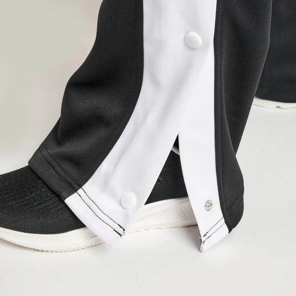 Close-up of the side tear-off buttons on the black Leone Stripe sweatpants