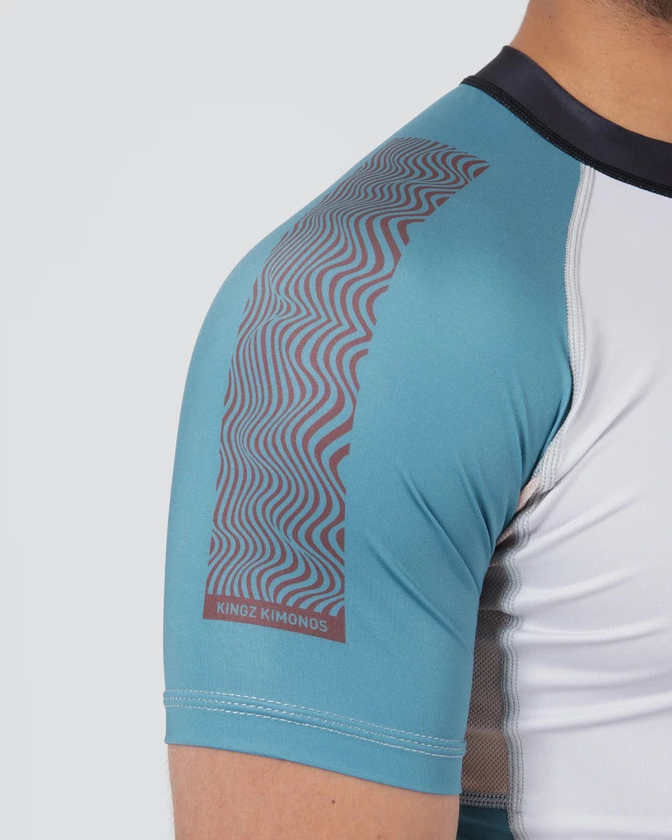 Detail van de schouder en versterkte stiksels op de lichtblauwe Kingz Flow rashguard