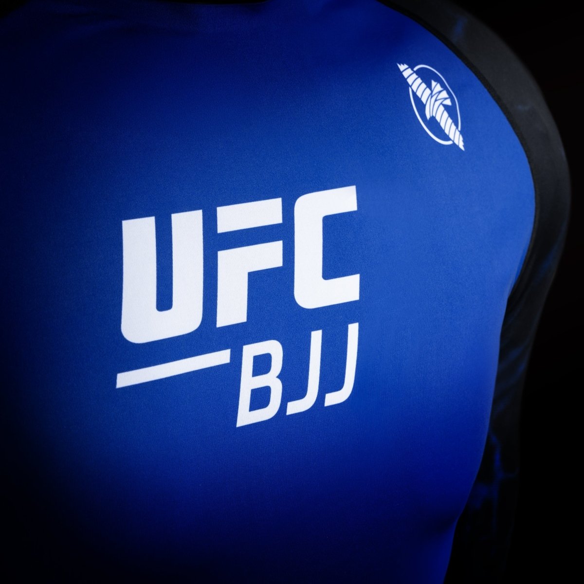 Detail of the UFC logo on the black and blue competition rash guard, detail of the high-resistance fabric